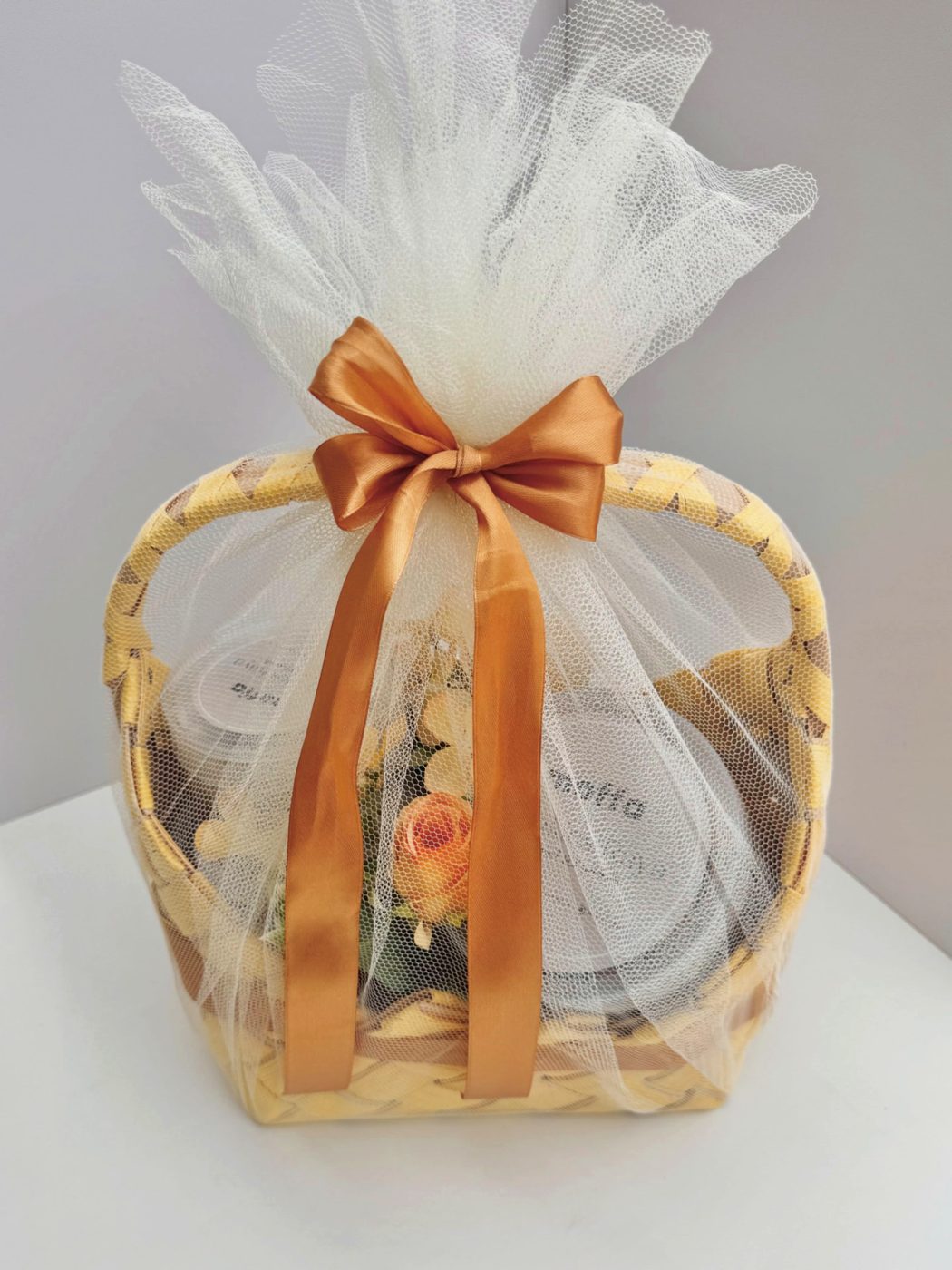 Gift hamper basket wrapped in tulle with a caramel bow